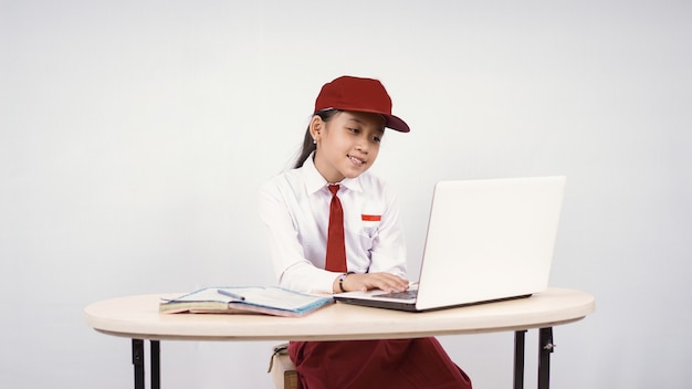 Menina asiática do ensino fundamental estudando on-line usando um laptop isolado no fundo branco