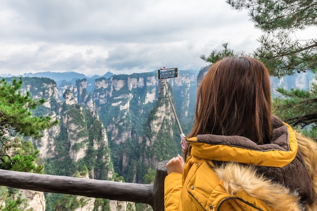 Menina asiática do turista que toma a foto usando o telefone esperto zhangjiajie wulingyuan changsha china