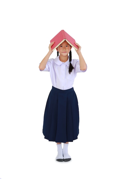 Menina asiática em uniforme escolar tailandês em pé com a capa do livro aberta sobre a cabeça isolada no fundo branco. Comprimento total com caminho de recorte