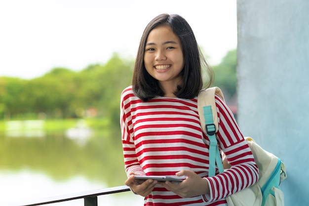 Foto menina asiática estudante com um tablet digital no parque em um dia ensolarado de verão