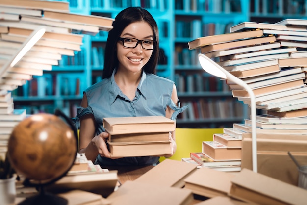 Menina asiática étnica que senta e que guarda livros.