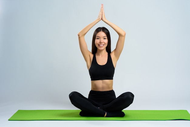 Menina asiática faz Yoga no tapete do ginásio. Pose De Lótus.