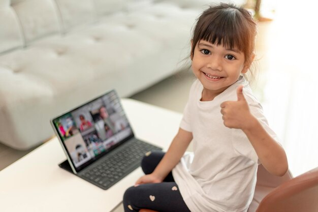 Foto menina asiática fazendo aulas on-line e feliz por conceito de pandemia de coronavírus de quarentena em casa