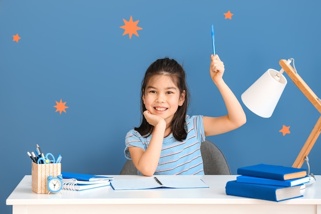 Menina asiática fazendo lição de casa à mesa