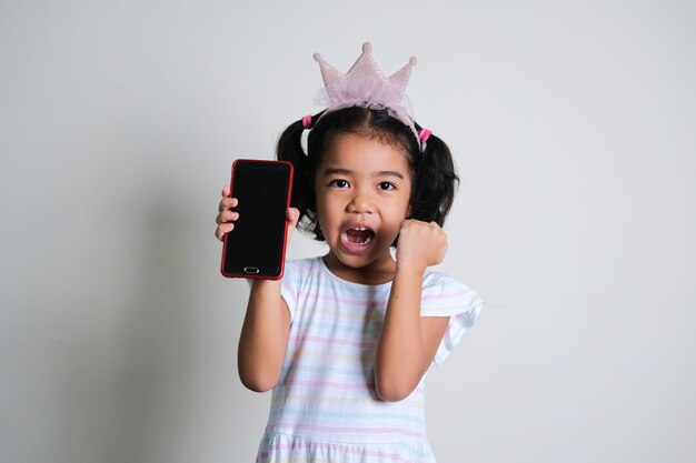 Foto menina asiática fazendo uma expressão animada enquanto mostra a tela do celular em branco