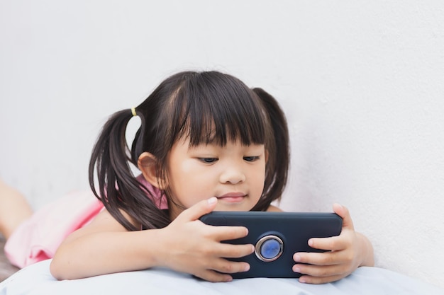 Menina asiática feliz assistindo e usando telefone inteligente