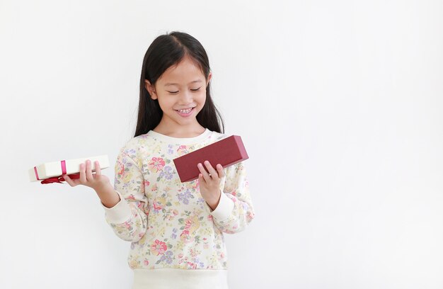 Menina asiática feliz enquanto abre a caixa de presente, feliz ano novo e conceito de feliz natal