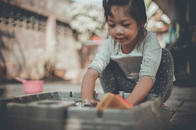 Menina asiática feliz jogando sujo com brinquedo de plástico ao ar livre