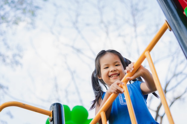 Menina asiática gosta de brincar em um parque infantil