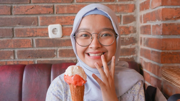 Menina asiática hijab enquanto desfruta de sorvete de gelato