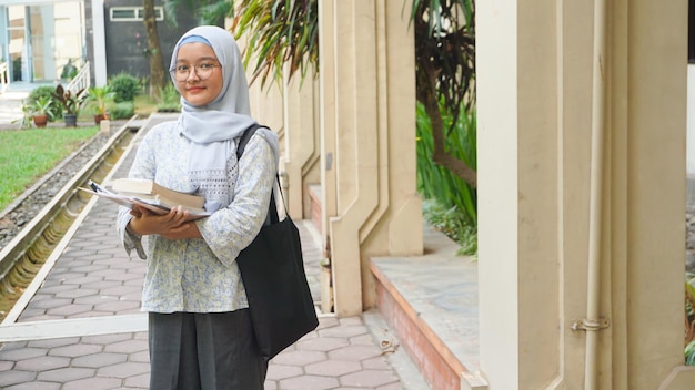 Menina asiática hijab que está estudando na universidade