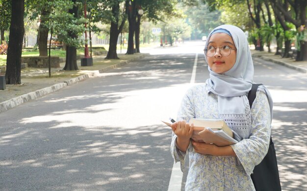 Menina asiática hijab que está estudando na universidade