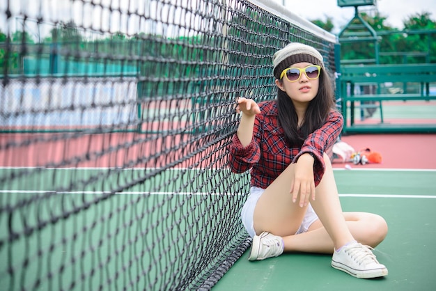 Menina asiática hipster posar para tirar uma fotoRetrato de moda mulher bonita na quadra de tênis estilo de vida da adolescente tailandesa moderna