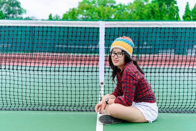 Menina asiática hipster posar para tirar uma fotoRetrato de moda mulher bonita na quadra de tênis estilo de vida da adolescente tailandesa moderna