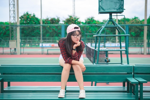 Menina asiática hipster posar para tirar uma fotoRetrato de moda mulher bonita na quadra de tênis estilo de vida da adolescente tailandesa moderna