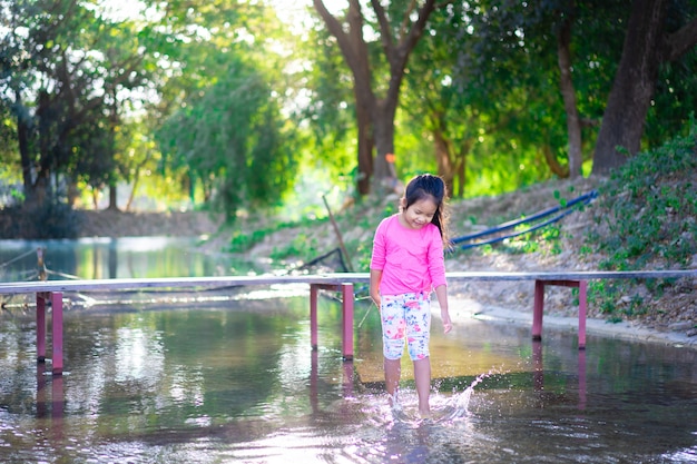 Foto menina asiática jogando água no parque de férias