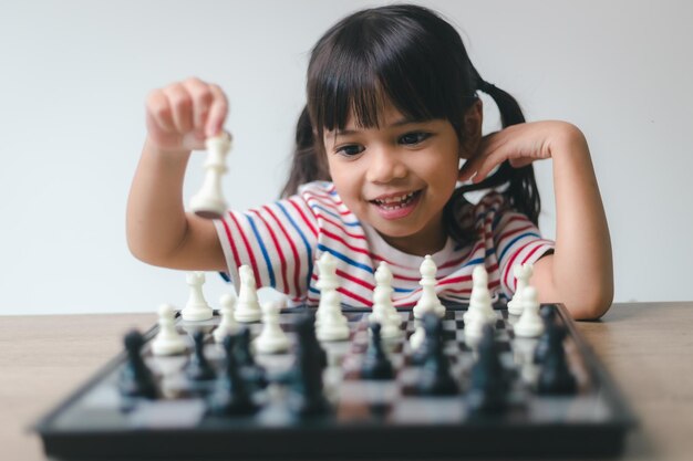 Menina asiática jogando xadrez em casa um jogo de xadrez