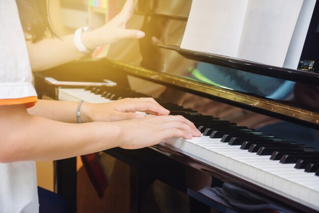 Menina asiática jovem praticar piano em casa