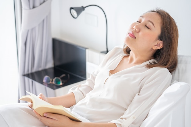 Menina asiática Leia livros enquanto dorme. Capa do livro do homem A sonolência causa sono.