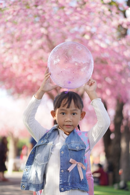 Menina asiática no jardim sob a flor da árvore de sakura