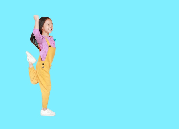 Menina asiática nos brins que saltam ou que correm sobre ciano com espaço da cópia.