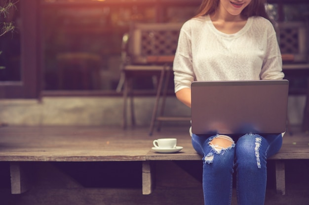 Menina asiática nova bonita que trabalha em uma cafetaria com um portátil. freelancer feminino