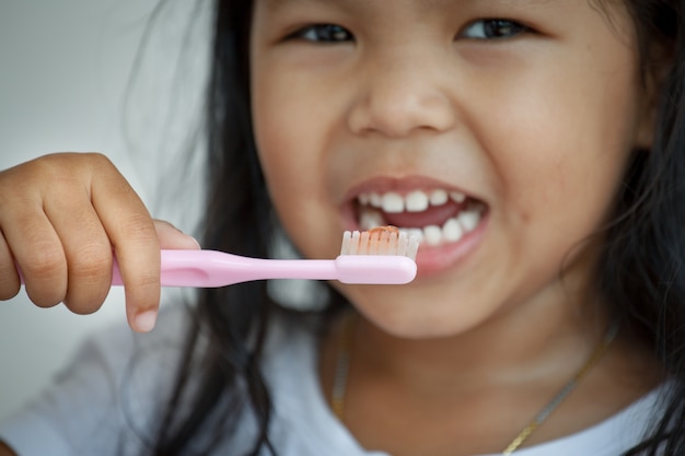 Menina asiática que escove os dentes. fechar-se