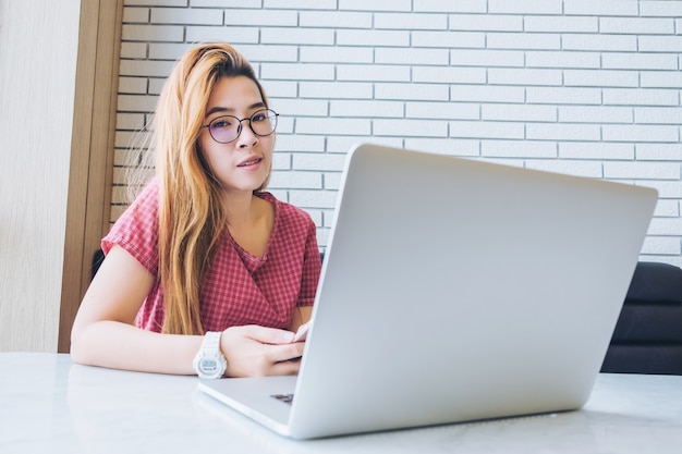 Menina asiática que trabalha em uma cafeteria com um freelancer laptop.female conectando-se à internet