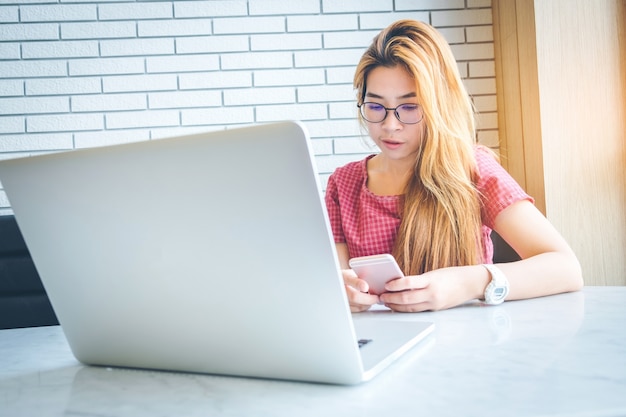 Menina asiática que trabalha em uma cafeteria com um freelancer laptop.female conectando-se à internet