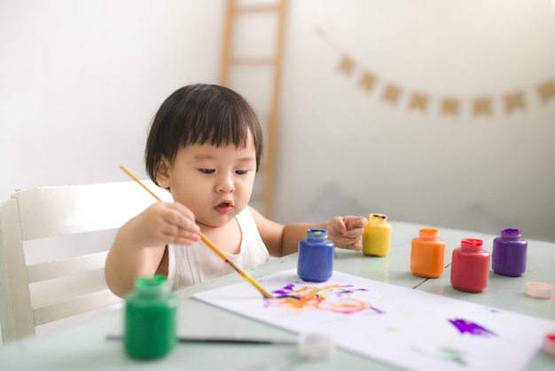 Menina asiática rindo engraçada desenhando com lápis coloridos em casa