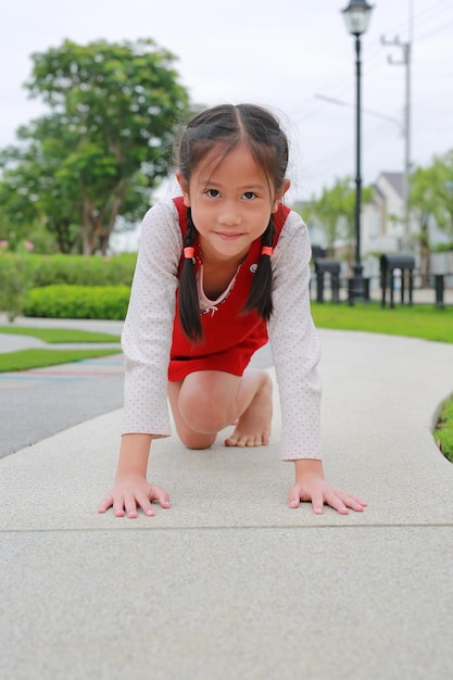 Menina asiática se preparando para correr no jardim Garoto se prepara para começar