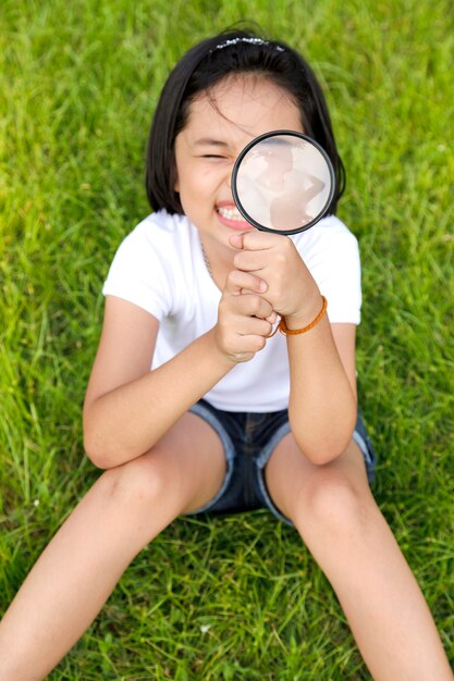 Menina asiática segurando uma lupa no exterior