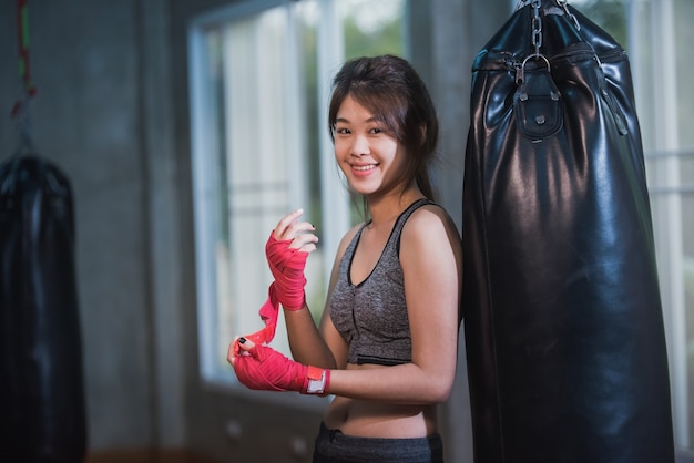 Menina asiática sexy perfurando saco de boxe