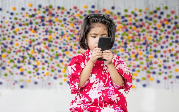 menina asiática sorria com fone de ouvido e celular