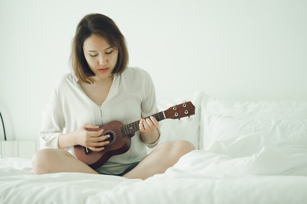 Menina asiática Tocar violão da manhã acordar