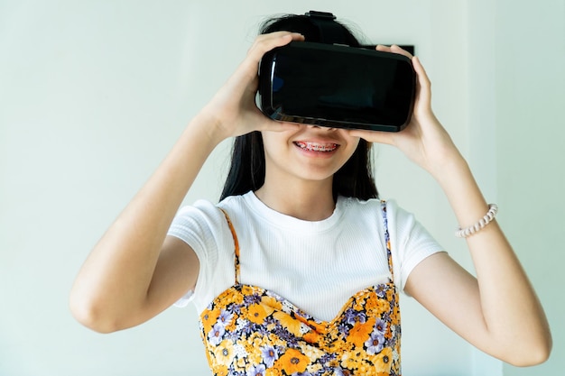 Foto menina asiática usando óculos vr com momentos excitantes e divertidos ela toca no fone de ouvido para ver um jogo de vedio