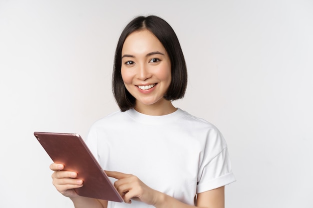 Menina asiática usando tablet digital trabalhando com compras de gadgets on-line sobre fundo branco