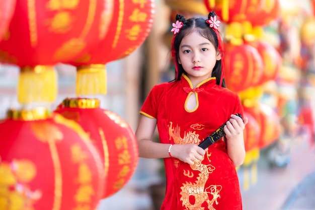 Menina asiática vestindo cheongsam chinês tradicional vermelho e segurando lanternas Fanningand com o alfabeto chinês Bênçãos escritas nele é uma decoração de elogio de bênção da fortuna para o ano novo
