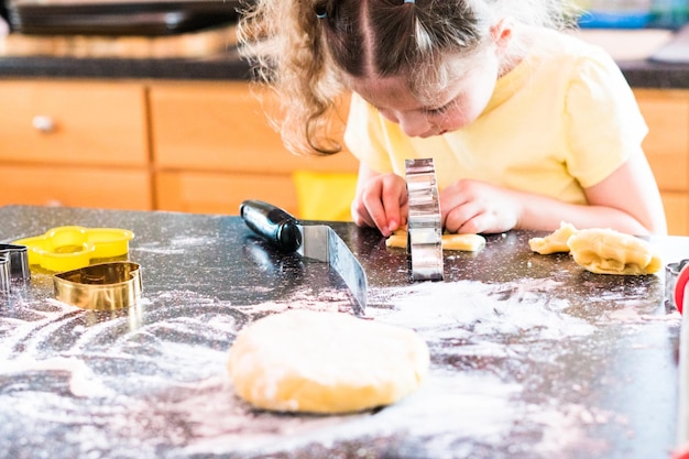 Menina assando biscoitos de açúcar na cozinha.