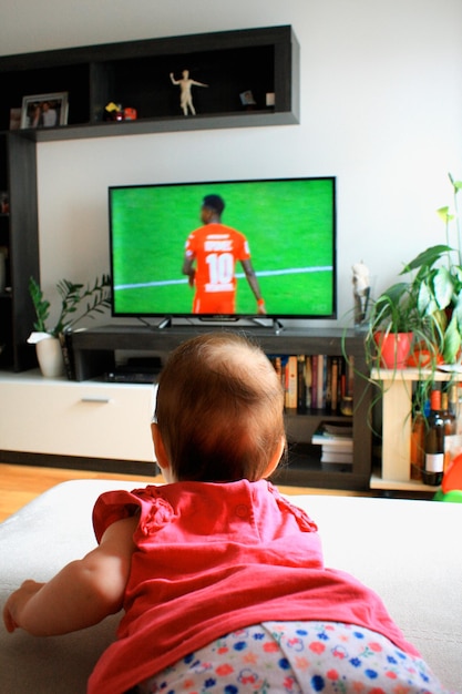 Menina assistindo a um futebol na tv