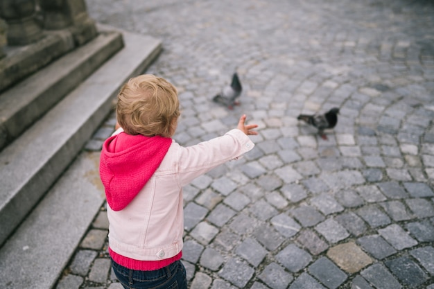 Menina assistindo pombos na praça