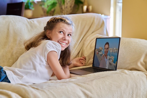 Menina assistindo transmissão de vídeo no laptop descansando deitado no sofá em casa