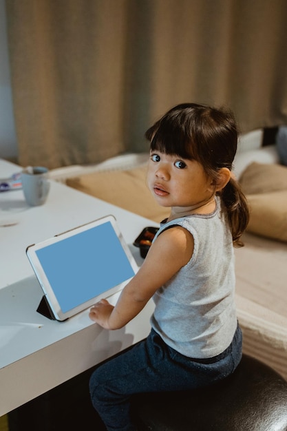 Foto menina assistindo vídeo em seu tablet em casa espaço de cópia de tela em branco
