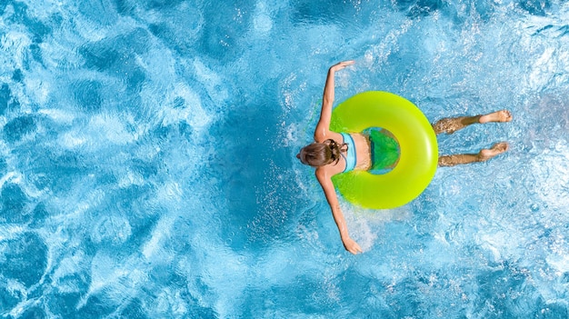 Menina ativa na vista aérea da piscina de cima, adolescente nada no anel inflável