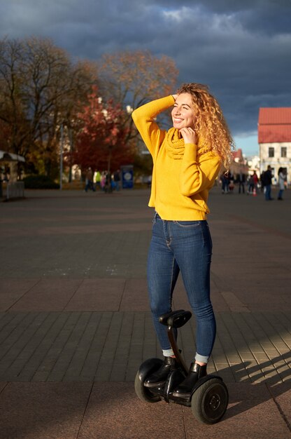 Menina atlética bonita nova do ajuste que monta no hoverboard na rua