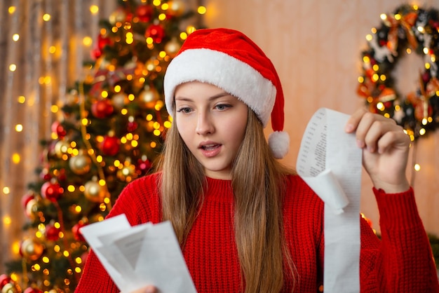 Menina atônita com cheque da última visita à loja para comprar presentes e decorações de Natal