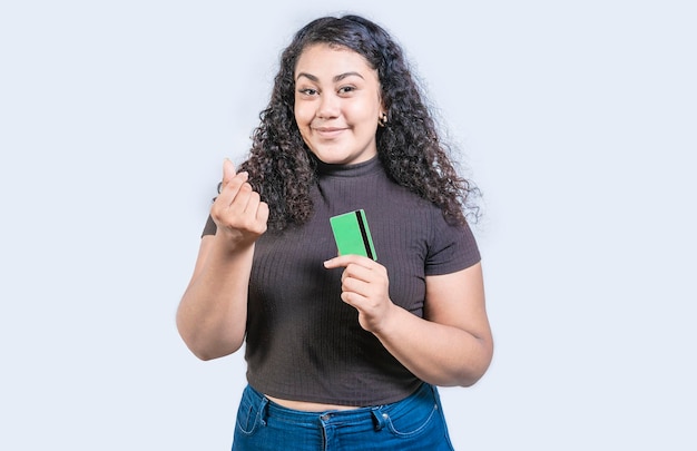 Menina atraente segurando cartão de crédito fazendo gesto de dinheiro com dedos isolados olhando para a câmera