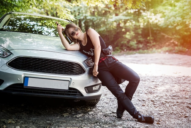 Foto menina bêbada ao lado do carro com uma garrafa de álcool nas mãos