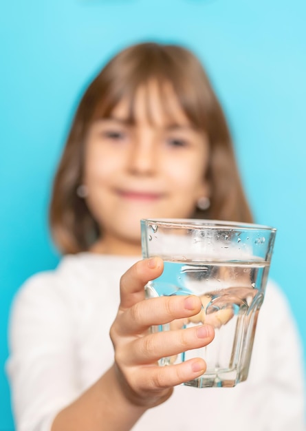 Menina bebe água de um copo Foco seletivo