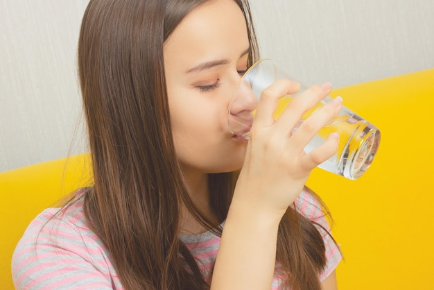 Menina bebe água em um copo